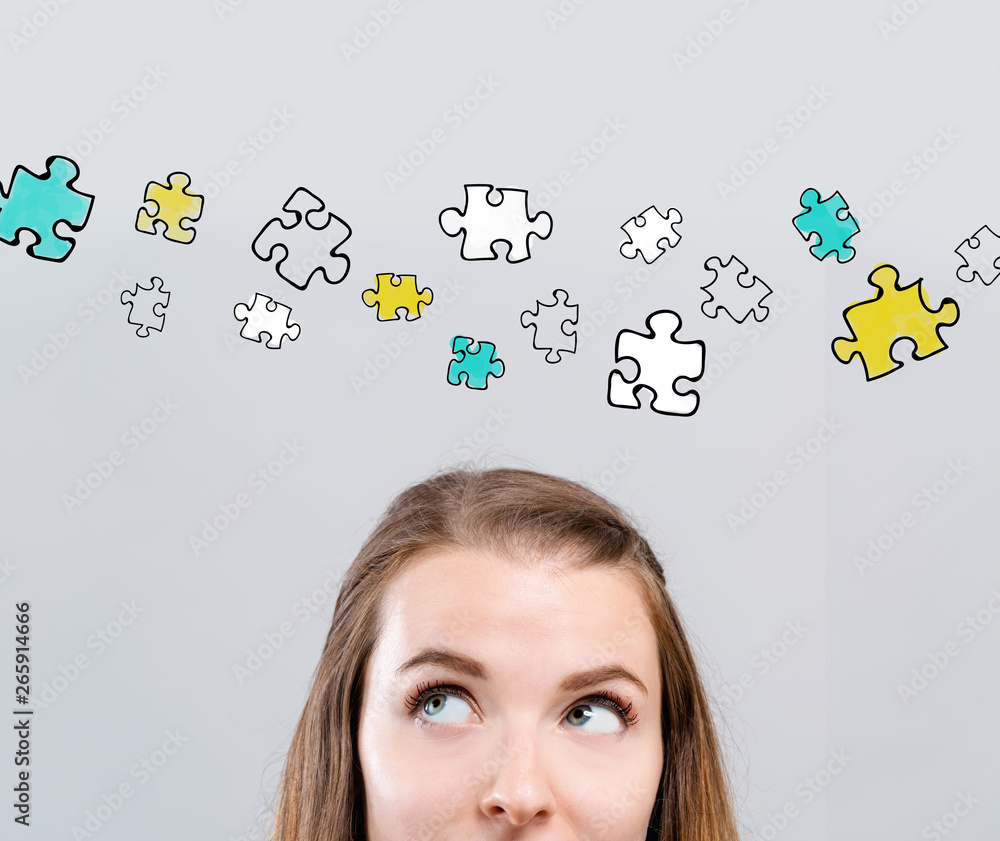 Puzzle pieces with young woman looking upwards