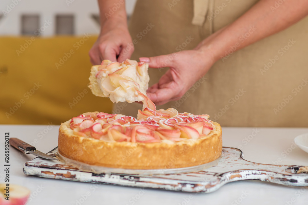 Woman cuts homemade apple cake, close-up. Pieces apple cake on a white wooden table. Delicious desse