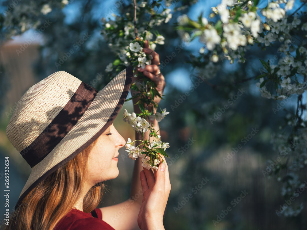 Cute girl in a hat enjoying the cherry blossoms in the garden