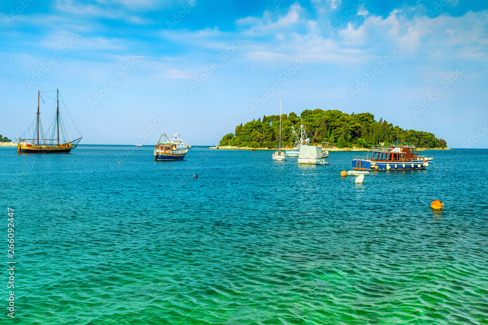 Tropical green island and boats on the sea, near Rovinj