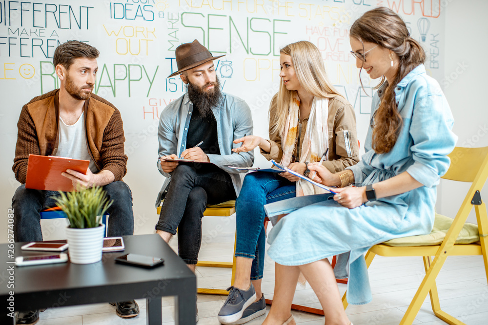 Group of people variously dressed writing some mental test during the psychological training, sittin