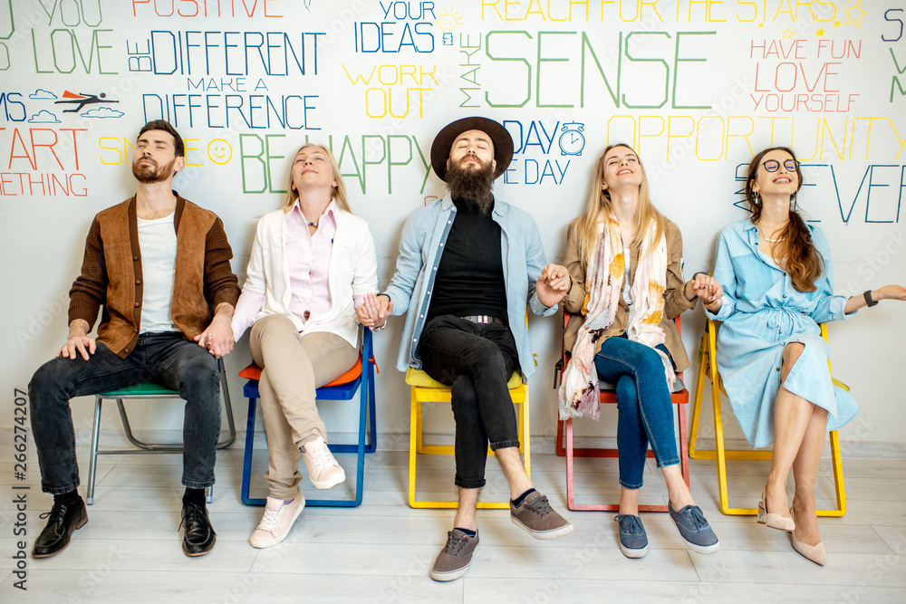 Group of people sitting in a row on the wall background with various inscriptions on the topic of me