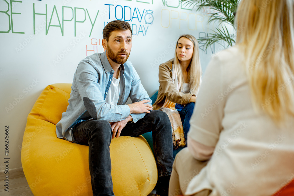 Young couple having misunderstandings during the psychological counseling with female psychologist i