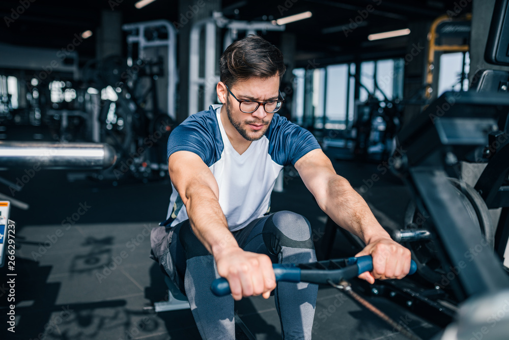 Handsome man in eyeglasses and sportswear exercising indoors.