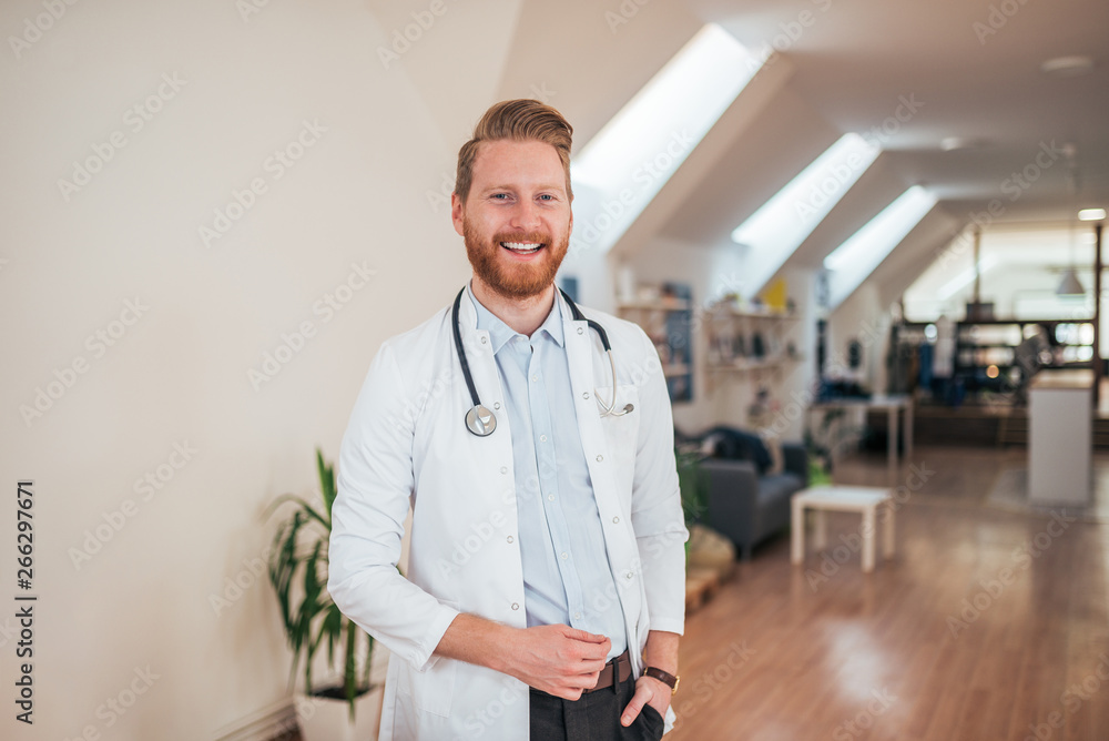 Portrait of young cheerful doctor in bright office.