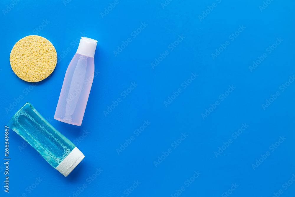 skin care cosmetics with facial tonic, mycelial water and sponge on blue background top view mockup