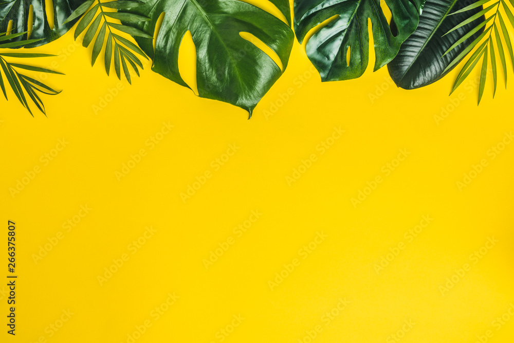 Tropical leaves on yellow background, space for text