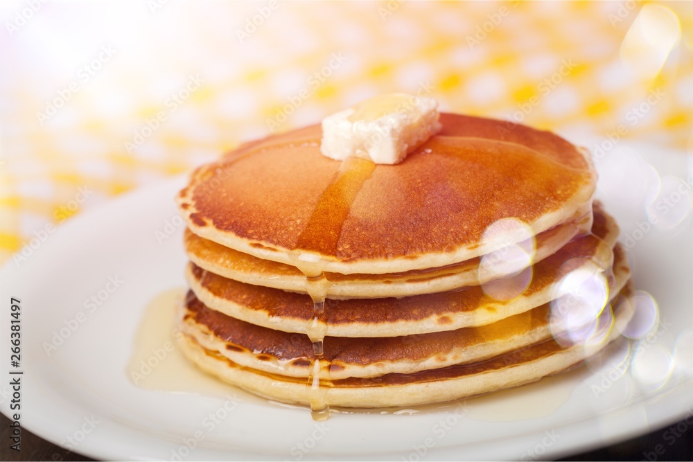 Stack of Small pancakes in syrup on background