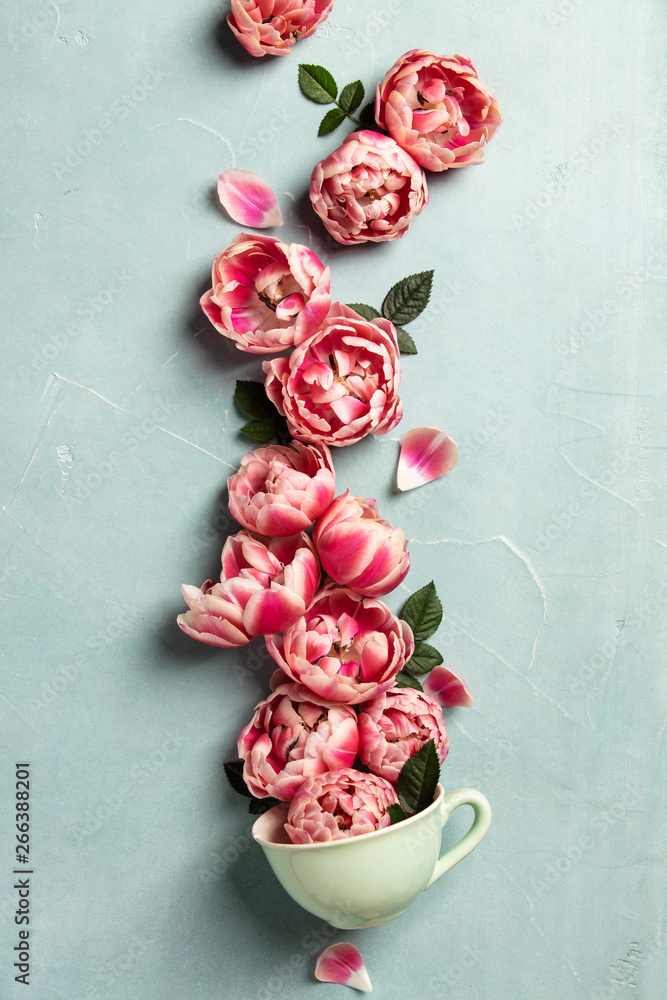 Creative layout made of coffee or tea cup with pink flowers on blue background