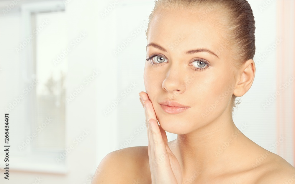 Portrait of young attractive woman touching her face and looking for acne