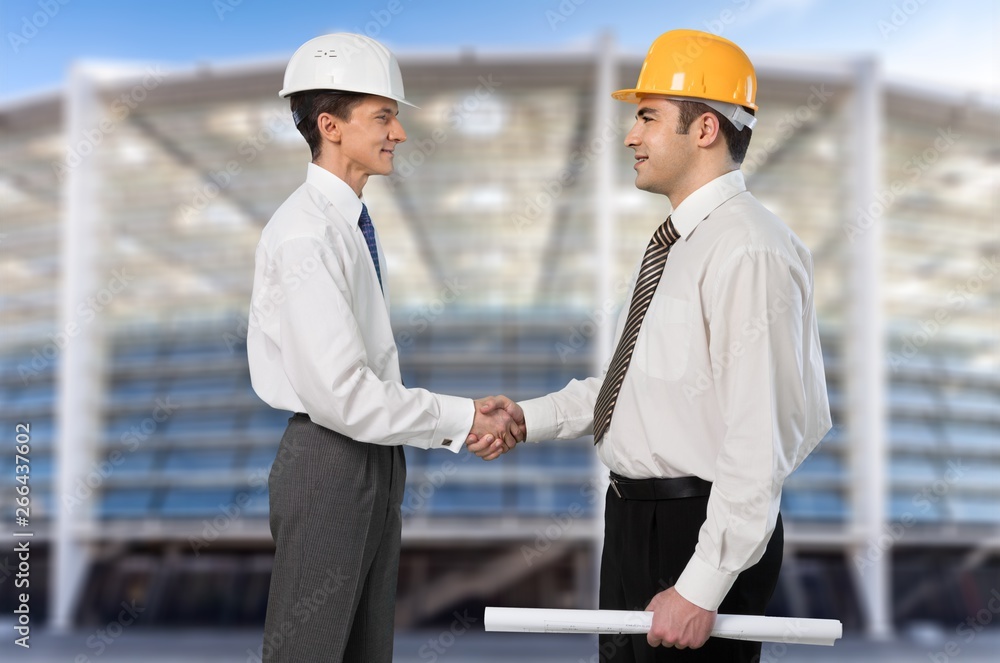 Two engineers men at construction site watching blueprint