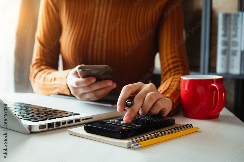 Businesswoman hands working with finances about cost and calculator and laptop with tablet, smartpho