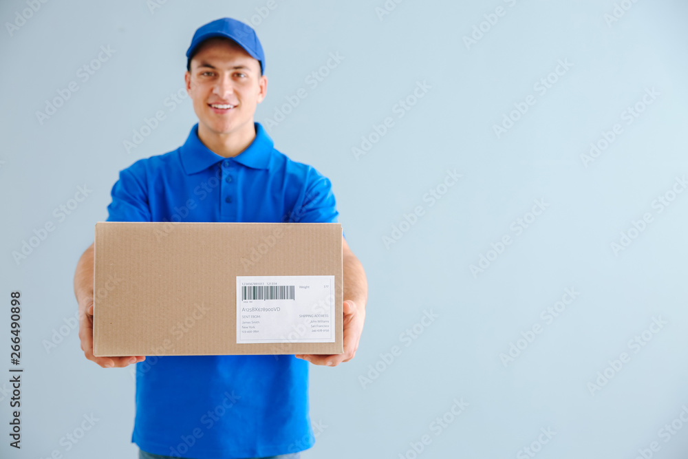 Delivery man with box on color background