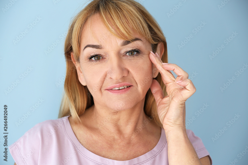 Mature woman with healthy skin on color background