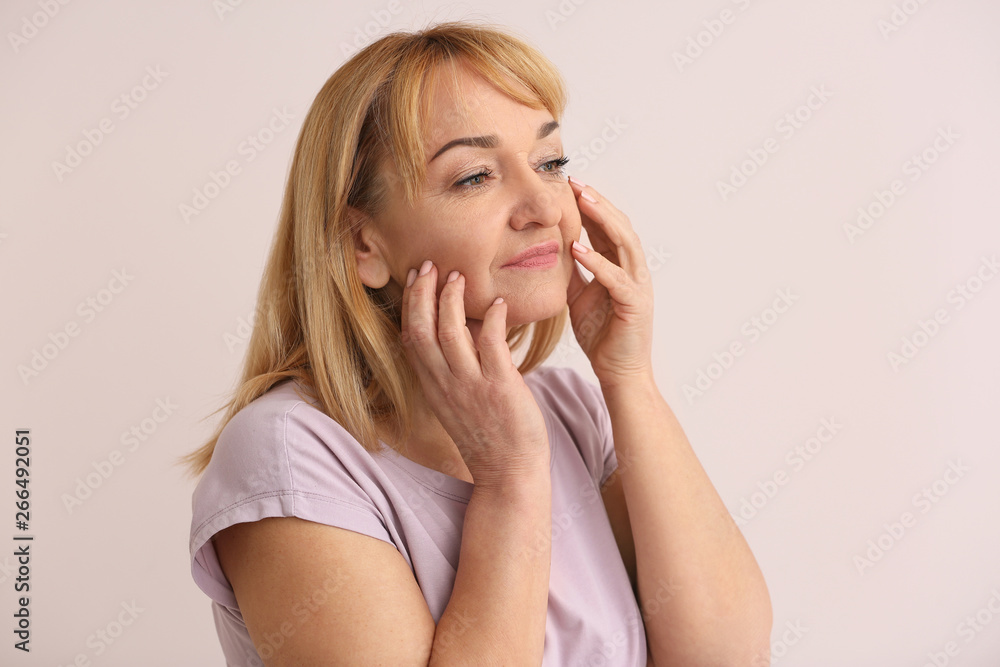 Mature woman with healthy skin on color background