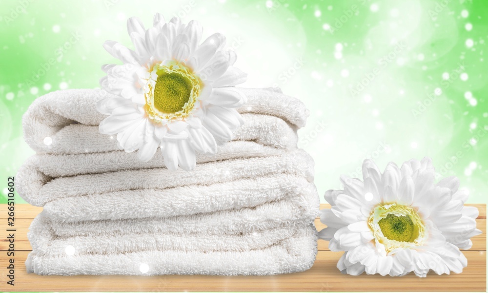 Pile of  fluffy towels with flowers on background