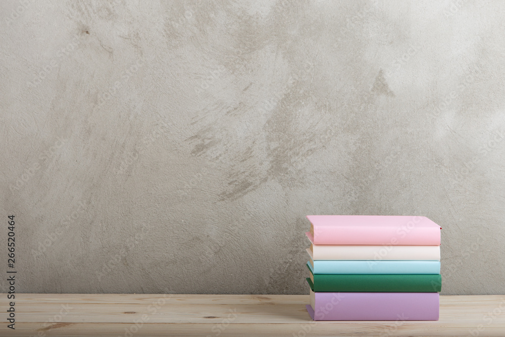 Education and reading concept - group of colorful books on the wooden table, concrete wall blackboar