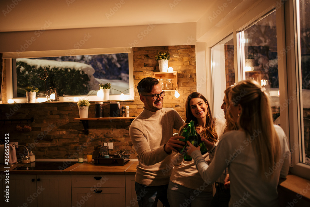 Group of friends doing celebratory toast with beer during house party