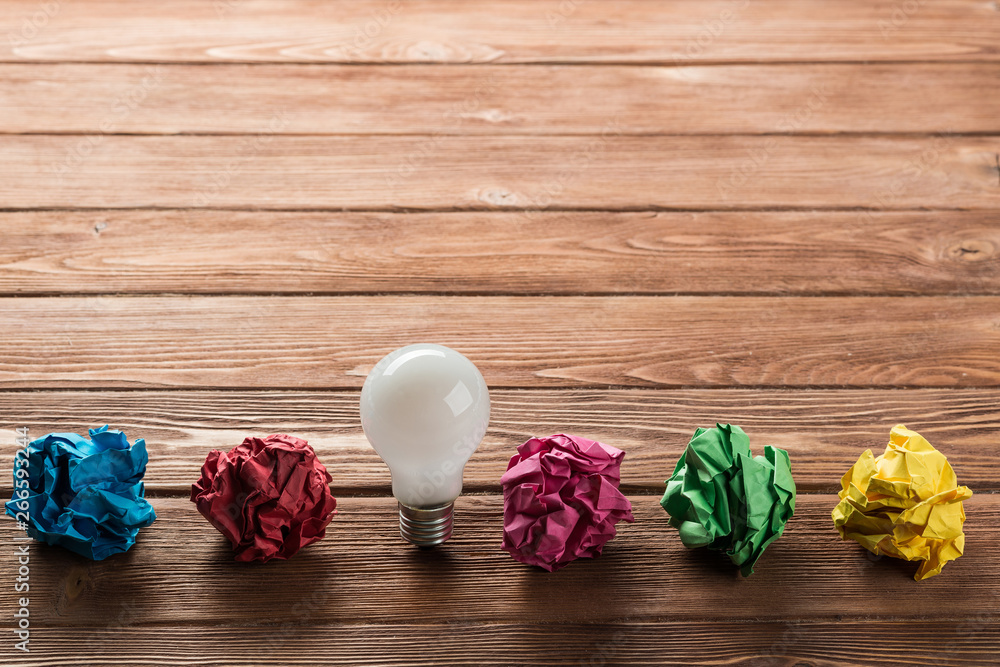 Ideological concept with wastepaper light bulb on wooden table