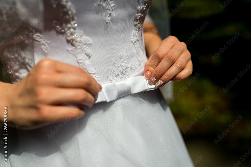 A close up of a bride dress with a large silk bow