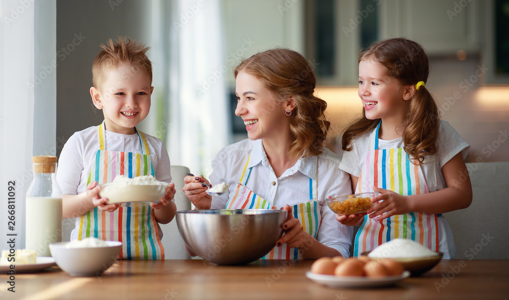 happy family in kitchen. mother and children preparing dough, bake cookies