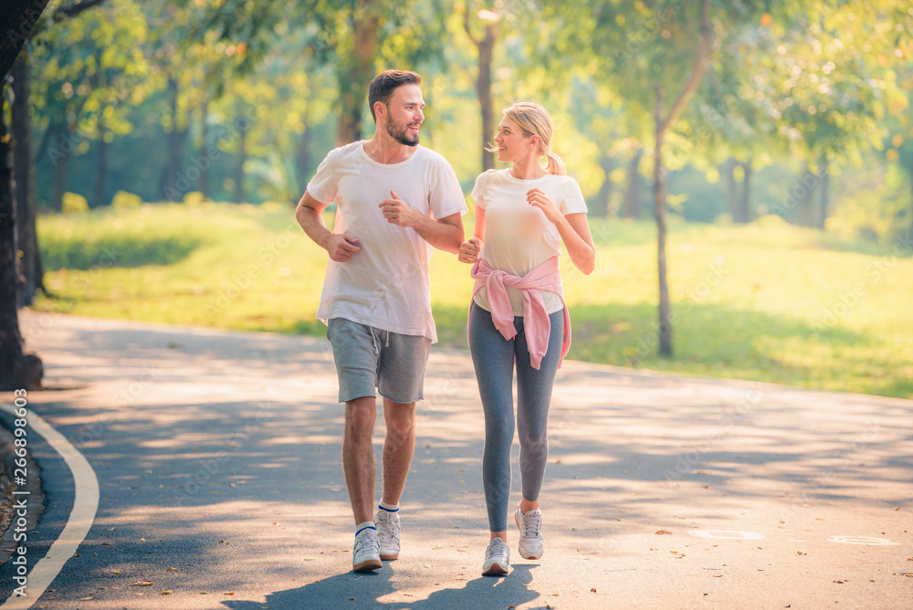 Portrait of Young couple running in the park at sunset. Concept sport and love. Warm tone.