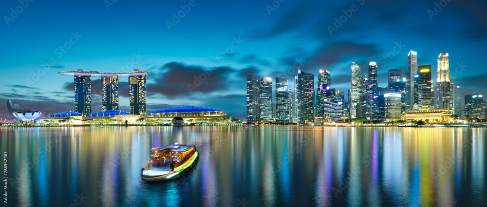 Panorama view of Singapore city skyline with tourist boat at night . Travel asia concept .