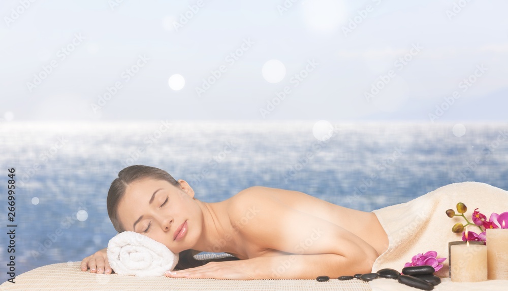 Beautiful young woman relaxing with stone massage at beauty spa