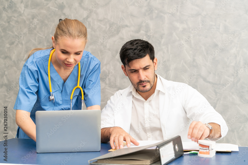 Doctor and nurse working with laptop computer in hospital office. Healthcare and medical concept.