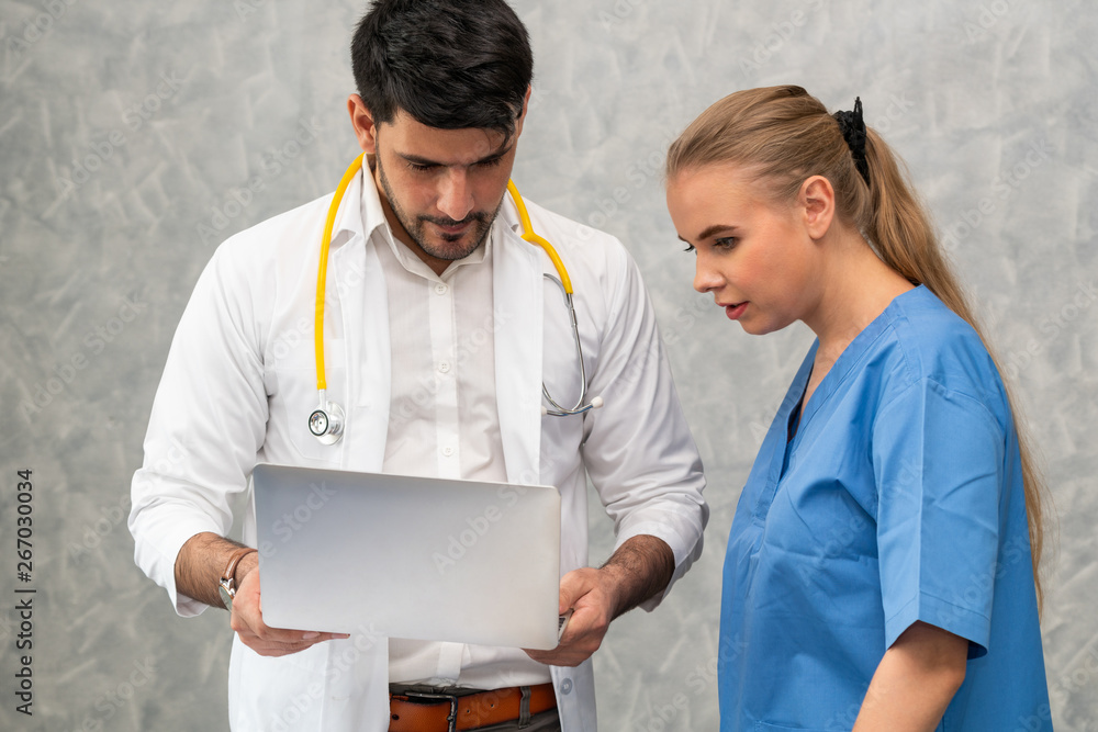 Happy doctor and nurse working with laptop computer in hospital office. Healthcare and medical conce