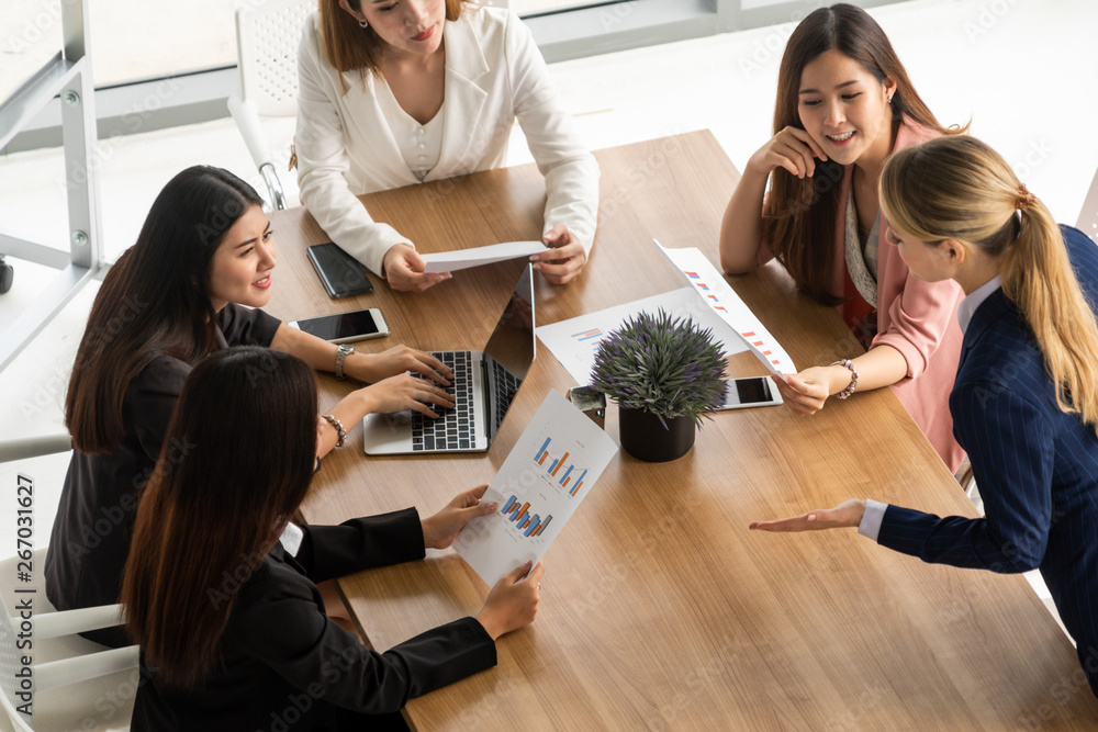 Businesswoman in group meeting discussion with other businesswomen colleagues in modern workplace of