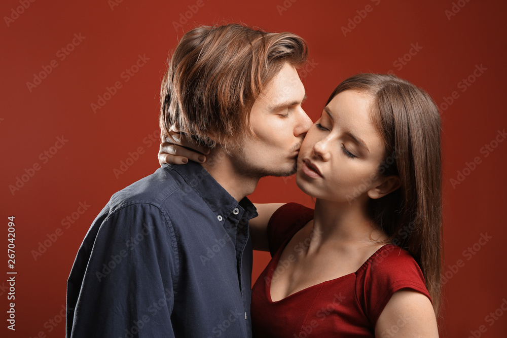 Kissing young couple on color background