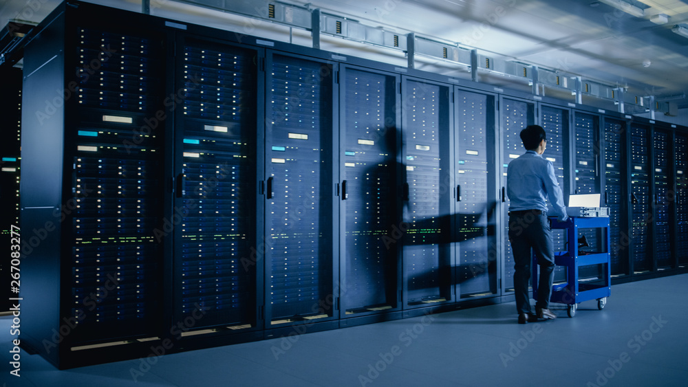 In the Modern Data Center: IT Engineer Doing Maintenance and Diagnostics. Pushes Cart alongside Serv