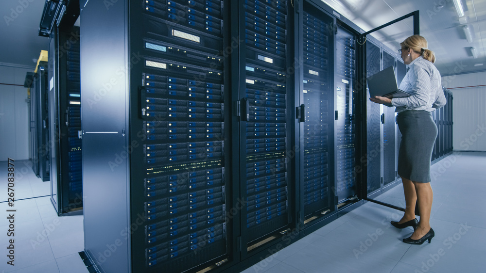 In Data Center: Female IT Technician Stand Near Opened Rack Cabinet and Runs Maintenance Program on 