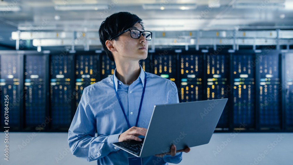 In the Modern Data Center: Portrait of IT Engineer Stand Near Server Racks, Finishing Maintenance an