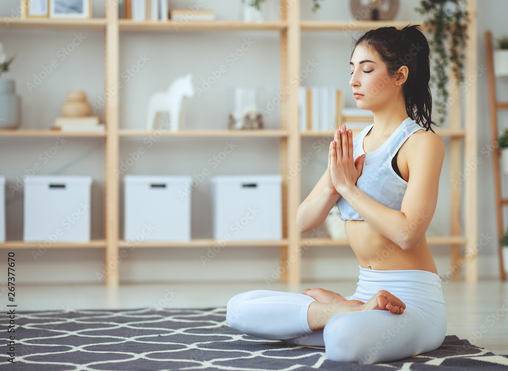 woman doing yoga, meditating in Lotus position at home