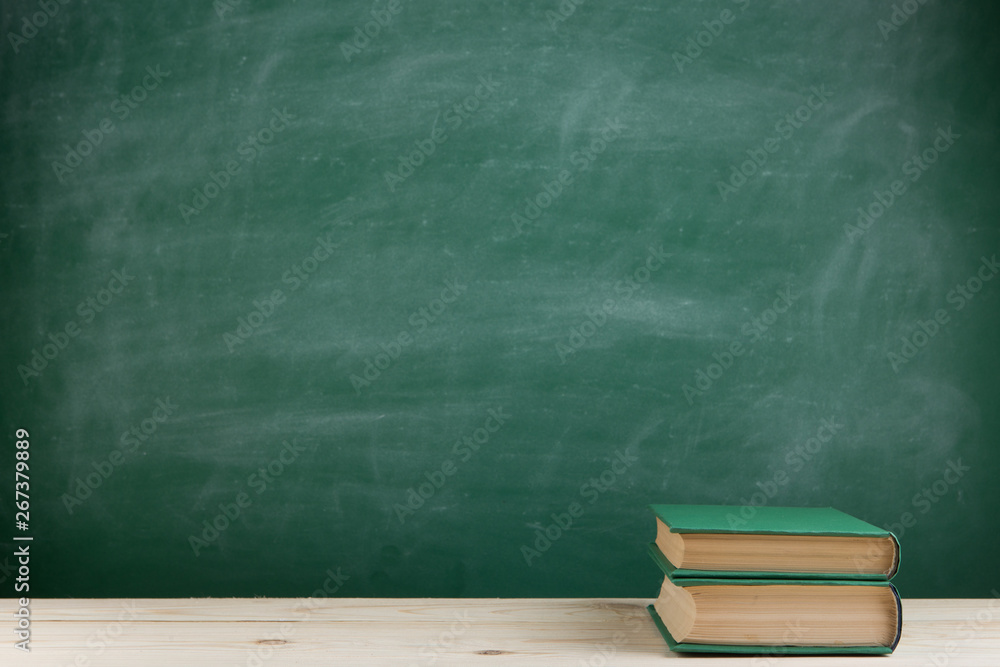 Education and reading concept - group of colorful books on the wooden table in the classroom, blackb