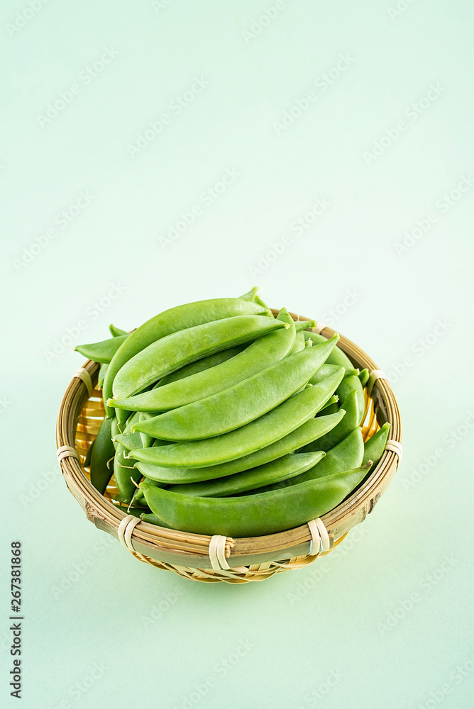 Fresh bamboo pod vegetable sweet bean poster background material in a bamboo sieve on light green ba