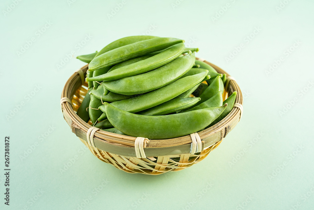 Fresh bamboo pod vegetable sweet bean poster background material in a bamboo sieve on light green ba