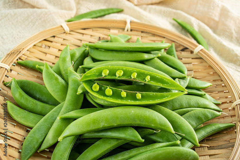 Fresh bean pod vegetable sweet beans on a bamboo sieve on a light green background