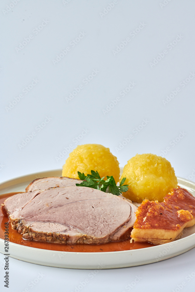 Deutscher Schweinebraten mit Kruste und Knödel auf weißem Hintergrund 