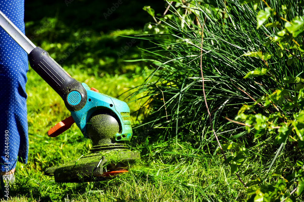 The simple mThoments of life, ordinary work in the garden -  man trimming grass with heavy-duty trim