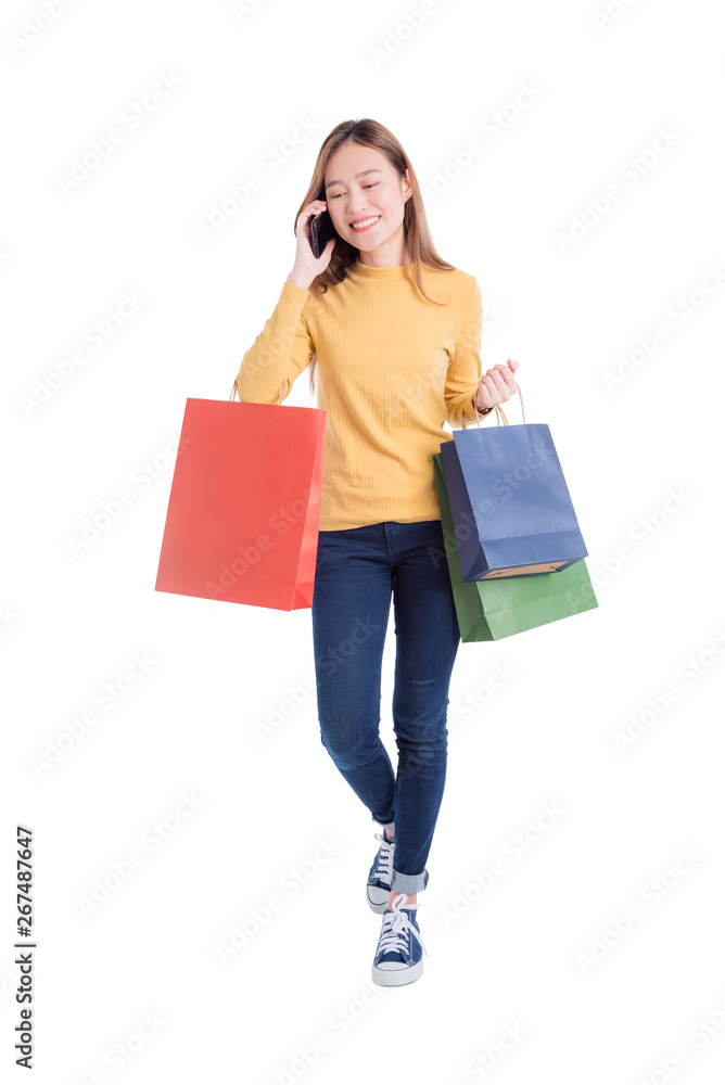 Full length of Beautiful asian woman holding many shopping bags and mobile phone isolated over white