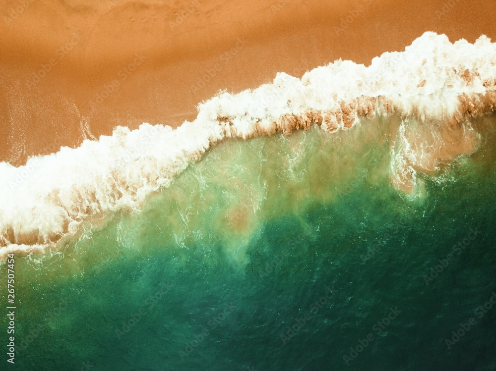 Beach on aerial drone top view with ocean waves reaching shore.