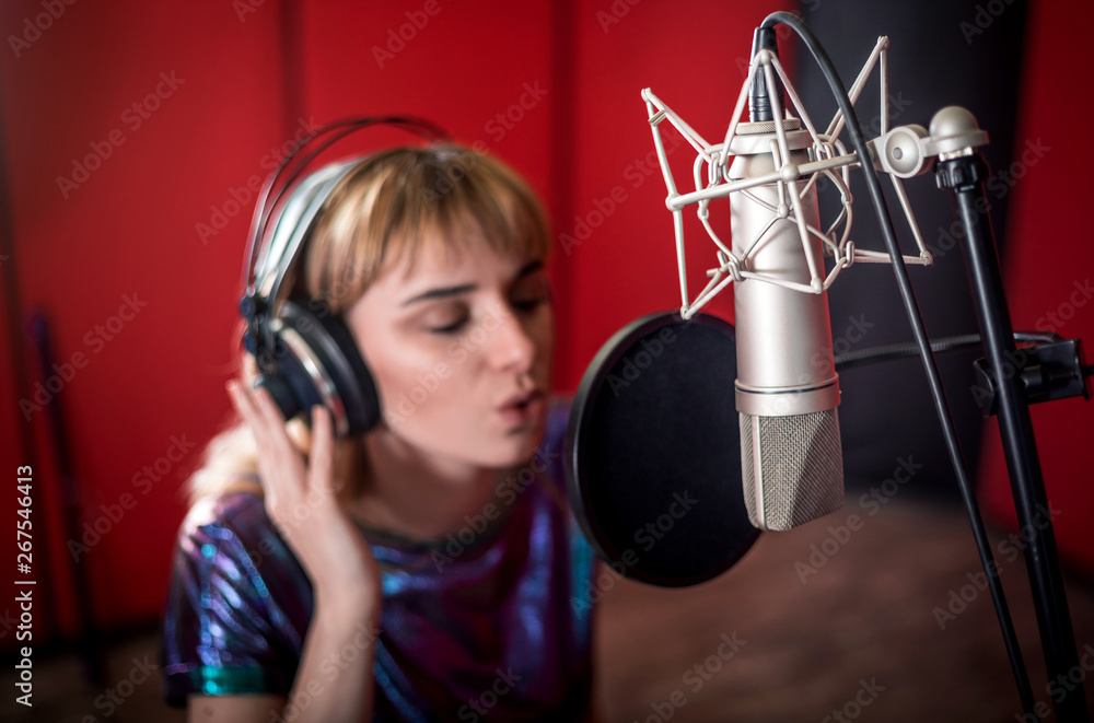 Female with microphone recording a voice for dubbing in music studio