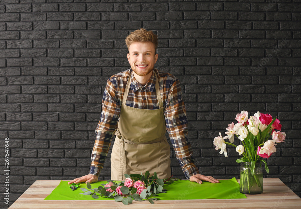 Handsome florist at table against dark background