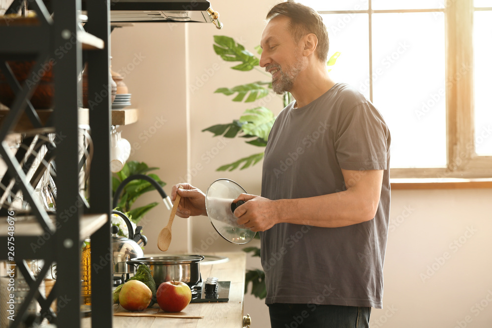 Handsome mature man cooking in kitchen