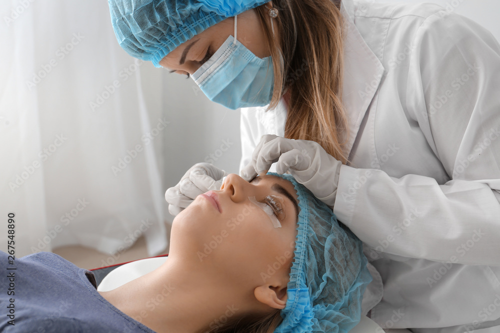 Young woman undergoing procedure of eyelashes lamination in beauty salon