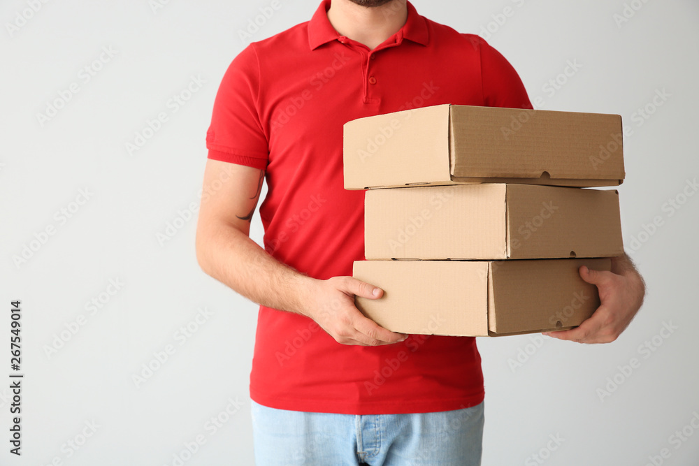 Delivery man with boxes on light background