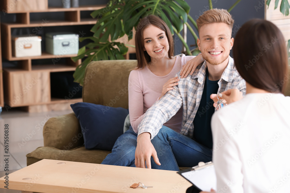 Real estate agent giving a key from new house to young couple